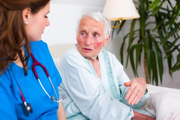 Vriendelijke verpleegster luisteren naar senior zieke vrouw — Stockfoto