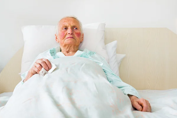 Sjuk och ledsen äldre kvinna om i sängen — Stockfoto