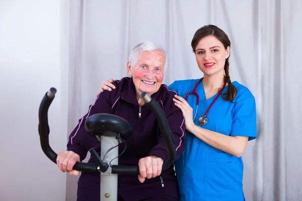 Freundliche Krankenschwester bei der Ausbildung einer Seniorin — Stockfoto