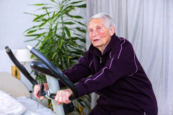 Senior vrouw op statoinary fiets spinnen — Stockfoto