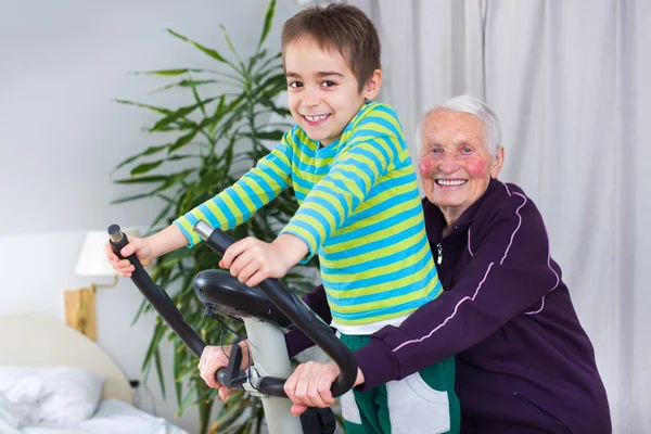 Grootmoeder training op hometrainer met kleinzoon — Stockfoto