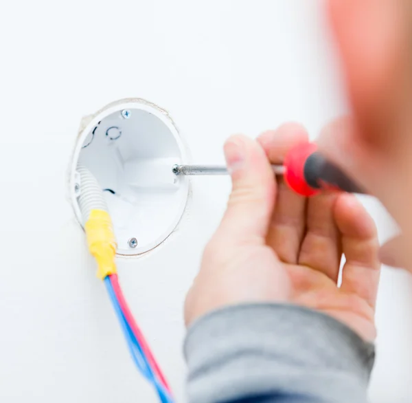 Elektricien isntalling licht op een muur — Stockfoto