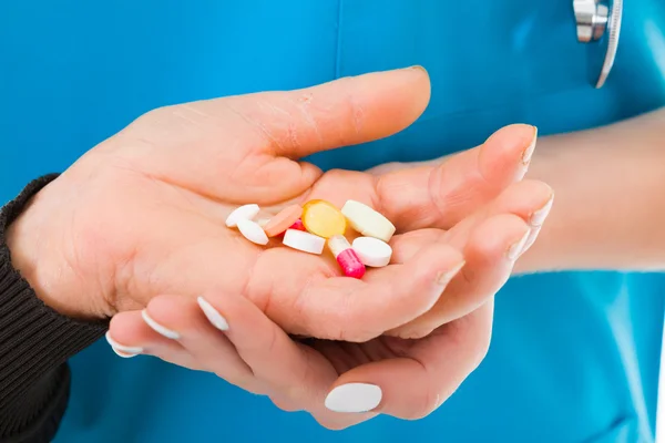 Elderly hands receiving different medications from the doctor — Stock Photo, Image