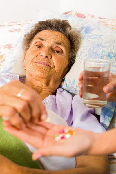 Suplementos nas mãos da enfermeira para a mulher idosa — Fotografia de Stock