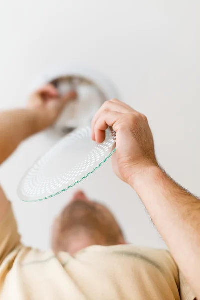 Repairman on ladder fixing light in the ceiling — Stock Photo, Image