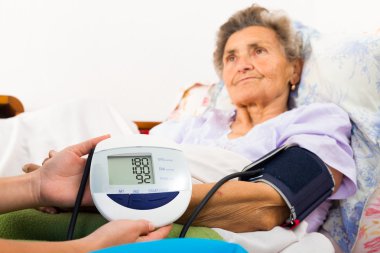 Hemşire hastanın kan basıncını ölçmek için yardım