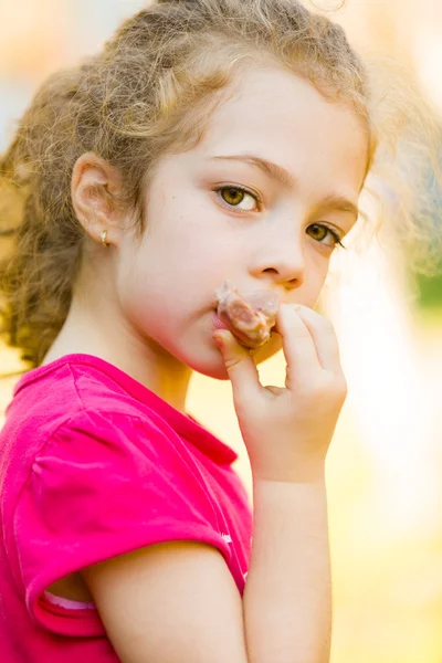 Meisje eten gekookt vlees op het bot buitenshuis — Stockfoto