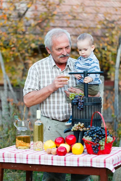 Morfar håller hans sonson med säsongens rik grödor — Stockfoto