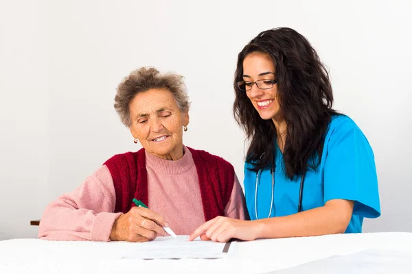 Verpleegkundige helpen oudere dame zingen overeenkomst — Stockfoto