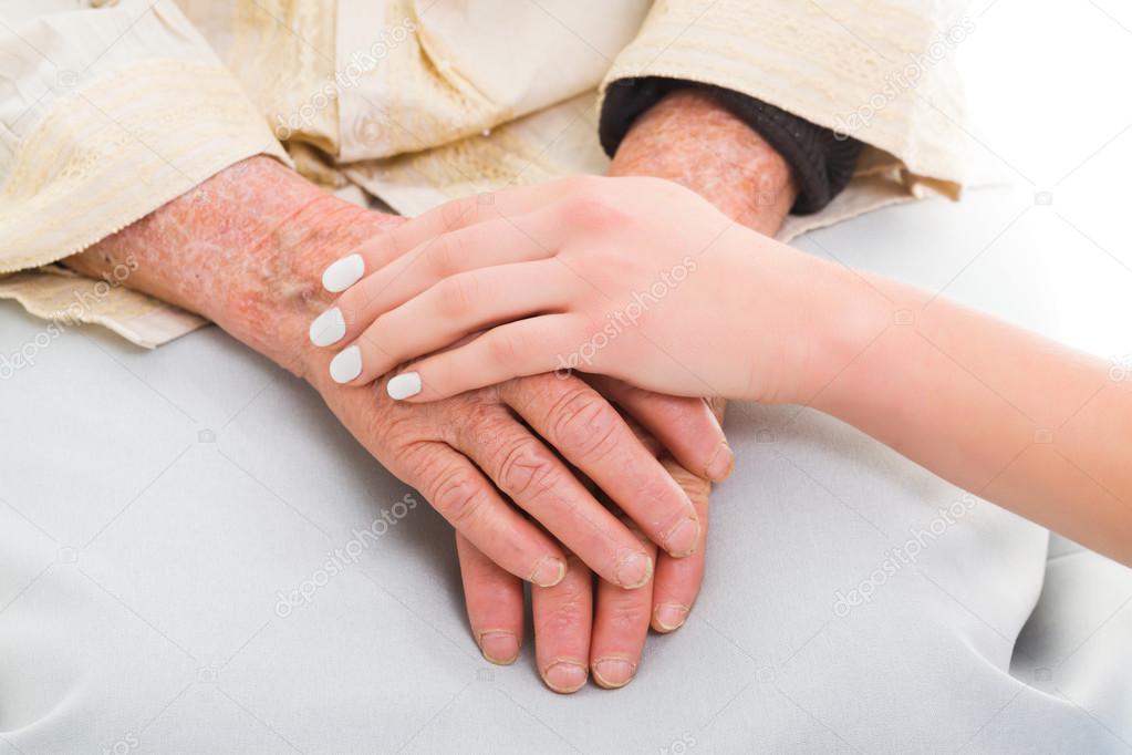 Elderly hands held by a young person
