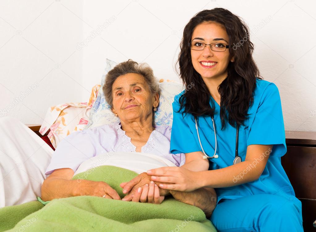 Health care nurse holding elderly lady's hand