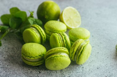 Kurabiyeler. Yeşil kireç ve nane yapraklı kurabiye. Lezzetli Fransız tatlıları. Makarnalar masaya.