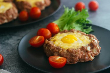 Tabakta yumurtalı biftek. Lezzetli sıcak yemek. Yemek kiraz domatesleri ve otlarla süslenmiş. Tabakta biftek. 