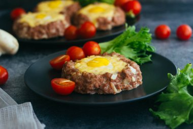 Tabakta yumurtalı biftek. Lezzetli sıcak yemek. Yemek kiraz domatesleri ve otlarla süslenmiş. Tabakta biftek. 