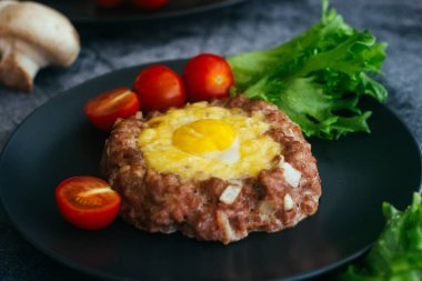 Tabakta yumurtalı biftek. Lezzetli sıcak yemek. Yemek kiraz domatesleri ve otlarla süslenmiş. Tabakta biftek. 