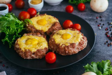 Tabakta yumurtalı biftek. Lezzetli sıcak yemek. Yemek kiraz domatesleri ve otlarla süslenmiş. Tabakta biftek. 