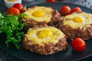 Tabakta yumurtalı biftek. Lezzetli sıcak yemek. Yemek kiraz domatesleri ve otlarla süslenmiş. Tabakta biftek. 