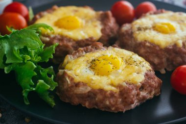 Tabakta yumurtalı biftek. Lezzetli sıcak yemek. Yemek kiraz domatesleri ve otlarla süslenmiş. Tabakta biftek. 