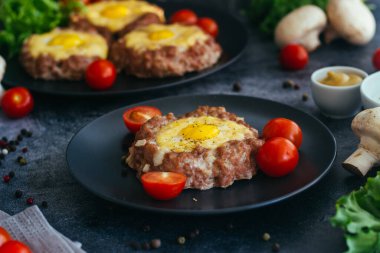 Tabakta yumurtalı biftek. Lezzetli sıcak yemek. Yemek kiraz domatesleri ve otlarla süslenmiş. Tabakta biftek. 