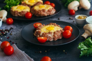 Tabakta yumurtalı biftek. Lezzetli sıcak yemek. Yemek kiraz domatesleri ve otlarla süslenmiş. Tabakta biftek. 