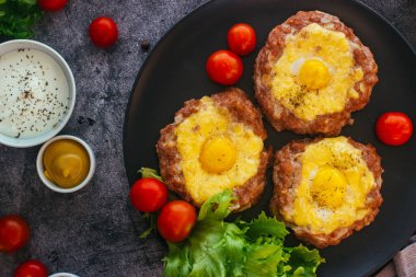 Tabakta yumurtalı biftek. Lezzetli sıcak yemek. Yemek kiraz domatesleri ve otlarla süslenmiş. Tabakta biftek. 