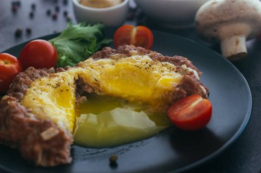 Tabakta yumurtalı biftek. Lezzetli sıcak yemek. Yemek kiraz domatesleri ve otlarla süslenmiş. Tabakta biftek. 