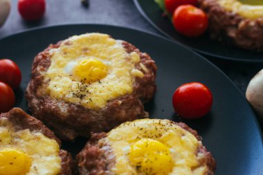 Tabakta yumurtalı biftek. Lezzetli sıcak yemek. Yemek kiraz domatesleri ve otlarla süslenmiş. Tabakta biftek. 