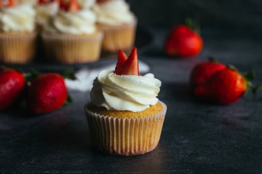 Lezzetli kekler. Krem peynirli ve çilekli kekler. Kekler beton bir masada. 