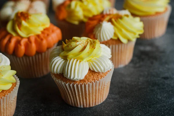 Delicious muffins. Orange and lemon cream muffins. Cupcakes on a concrete table 