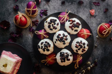 Paskalya pastası. Paskalya için geleneksel bir Ortodoks yemeği. Kurutulmuş kayısı, kuru üzüm ve kremalı Paskalya pastaları. Boyalı yumurtalarla Paskalya kompozisyonu 
