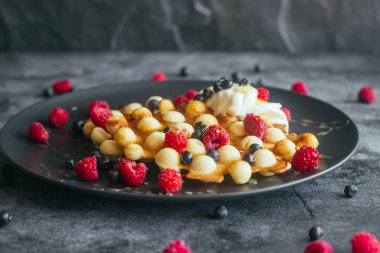 Lezzetli Hong Kong waffle 'ları. Ahududulu waffle, yaban mersini, ekşi krema ve bal. Masada waffle var. 