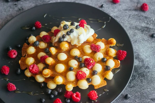 Lezzetli Hong Kong waffle 'ları. Ahududulu waffle, yaban mersini, ekşi krema ve bal. Masada waffle var. 