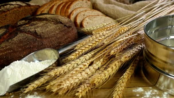 Pan, gavilla de espigas de trigo y harina en una mesa de madera, muñeca, vista superior — Vídeos de Stock