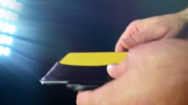 Futbol / futbol hakem siyah arka plan üzerine ceza sarı kartı gösterir