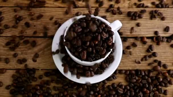 Movimento lento de derramar grãos de café em uma xícara em uma mesa de madeira velha, vista superior — Vídeo de Stock