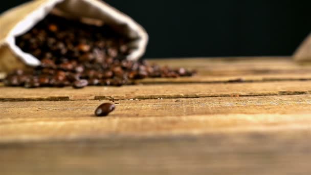 Movimento lento de grãos de café caindo sobre mesa de madeira — Vídeo de Stock