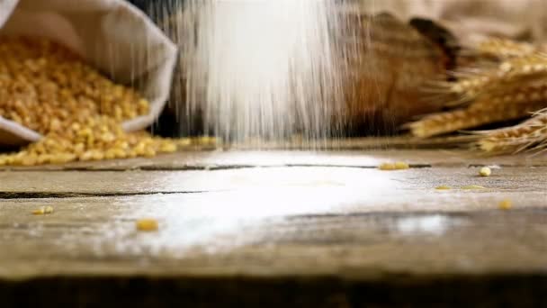 Mouvement lent du tamisage de la farine sur la table en bois, les grains de blé et le pain sur le fond — Video