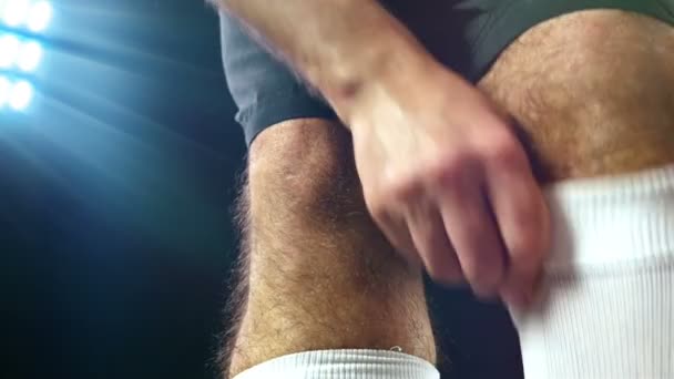 Fútbol, juego de fútbol. Futbolista profesional ajustando sus calcetines, fondo negro — Vídeo de stock