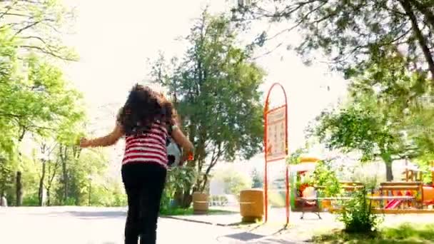 Jovem com bola de futebol correndo para um playground — Vídeo de Stock