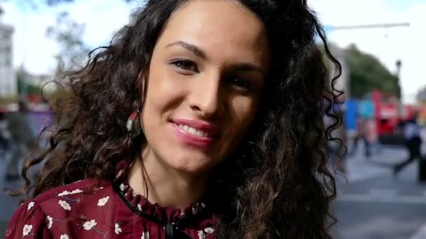 Portrait of happy young woman with beautiful curly hair smiling in the city, slow motion — Stock Video