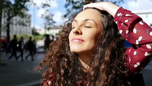 Портрет щасливої молодої жінки з красивим кучерявим волоссям, що посміхається в місті, повільний рух — стокове відео
