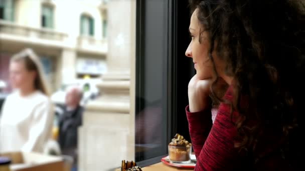 Portrait de jeune femme heureuse avec de beaux cheveux bouclés assis dans un café, au ralenti — Video