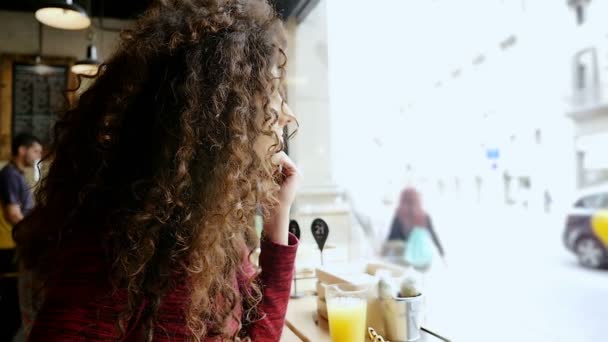 Porträtt av lycklig ung kvinna med vackra lockigt hår sitter i Café, slow motion — Stockvideo