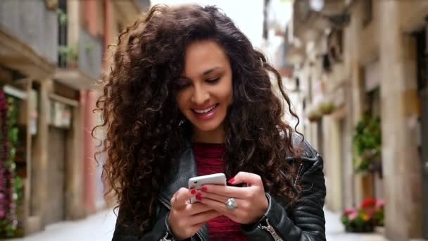 Portrait de jeune femme avec téléphone intelligent marchant dans les rues de la ville, ralenti — Video