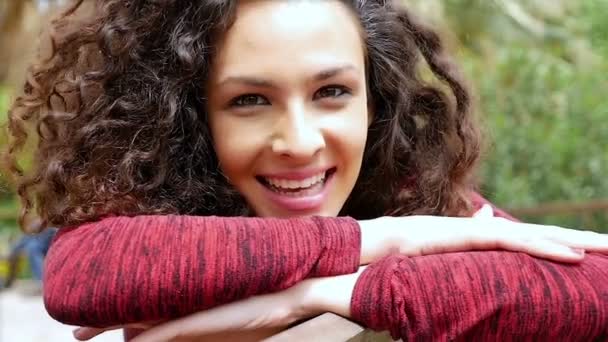 Portrait of happy young woman with beautiful curly hair leaning head on her arms, slow motion — Stock Video