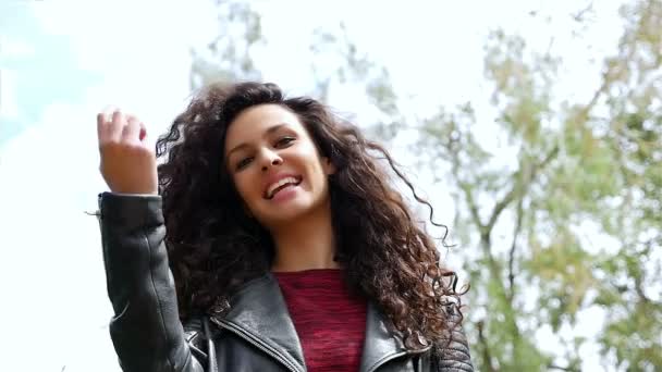 Portrait d'une jeune femme heureuse aux beaux cheveux bouclés souriant dans un parc, au ralenti — Video