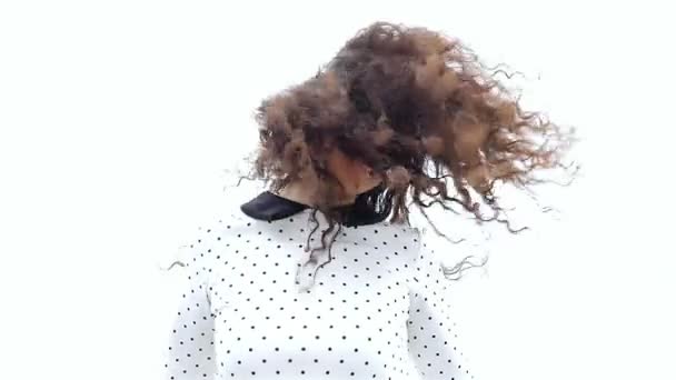 Jovem mulher sacudindo seu belo cabelo encaracolado no fundo branco, câmera lenta — Vídeo de Stock