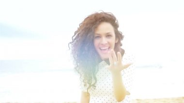 Güzel kıvırcık saçlı genç kadın beni takip et ve kumsalda koş, ağır çekimde.