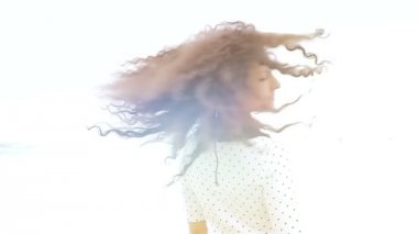 Beyaz arka planda güzel kıvırcık saçlarını sallayan genç bir kadın.