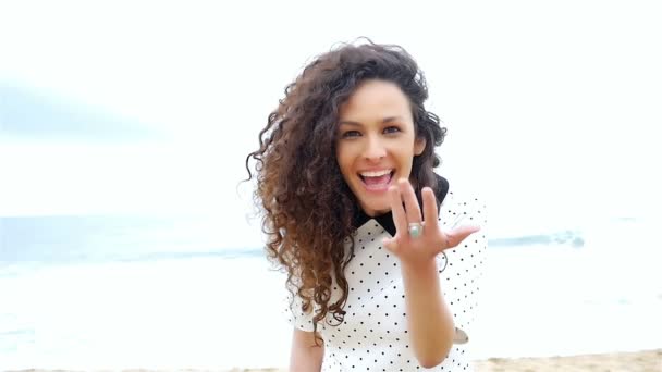Молодая женщина с красивыми вьющимися волосами жестом следовать за мной и бегать по пляжу, замедленное движение — стоковое видео
